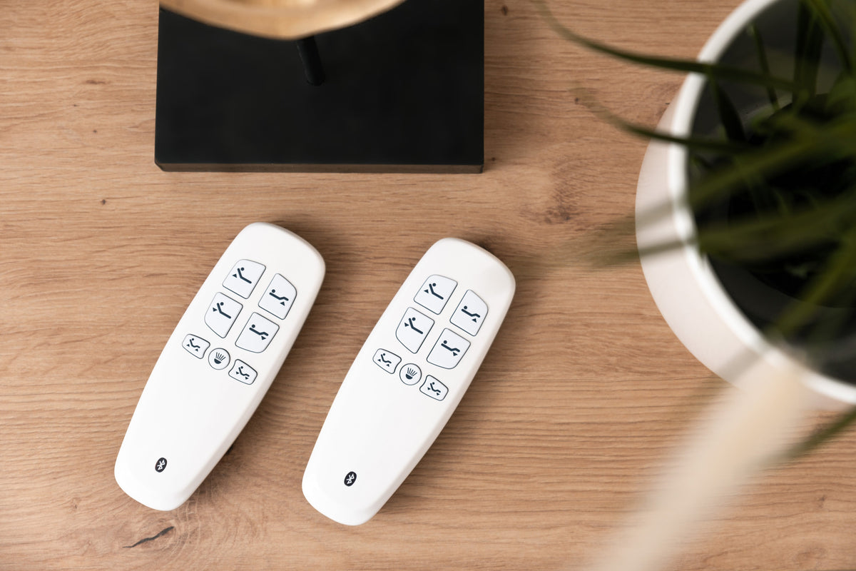 Deux télécommandes de sommier électrique posées sur une table